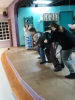 The Steel Magnolias cast practicing the "Hit her!" scene, breaking the tension of the moment with laughter.